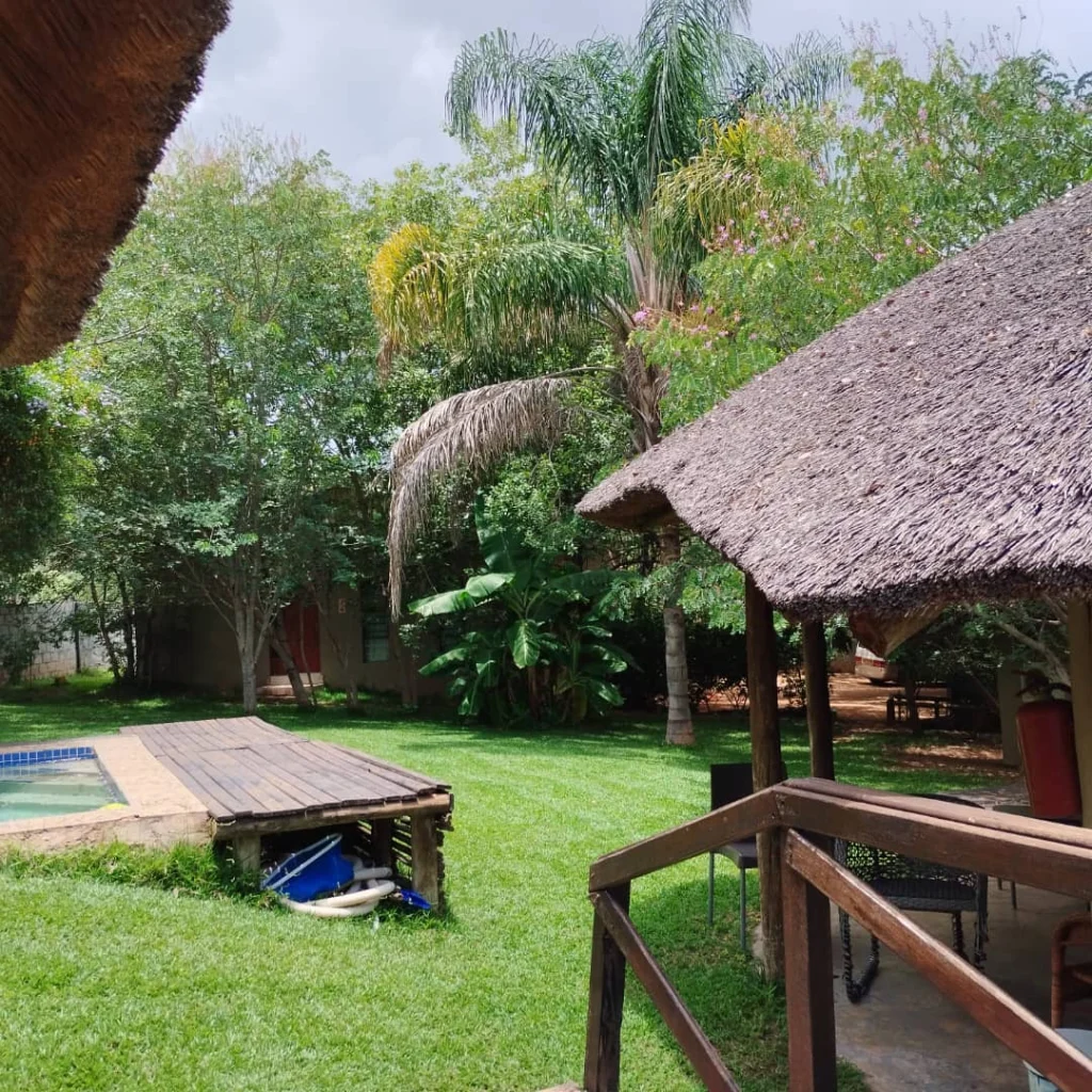 “Wide shot of Chobe Sunset Chalets surrounded by green landscaping and pathways under late afternoon light.”